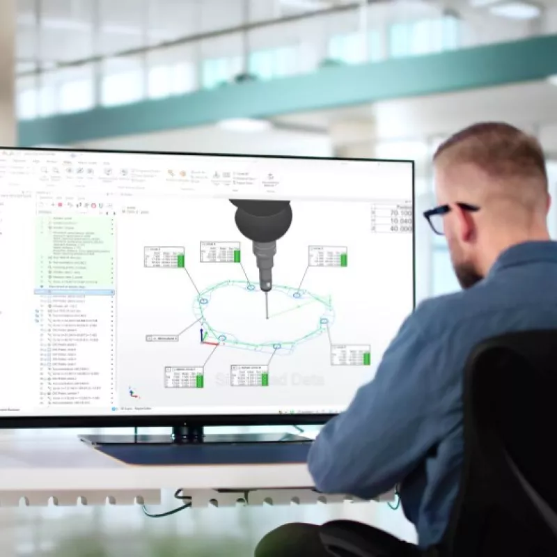 A metrologist leveraging PolyWorks|Inspector's no-code CMM programming workflow while viewing a 3D CAD model on a screen.