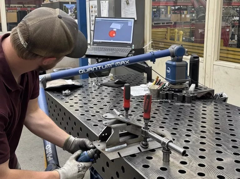 A technician performing 3D inspection on a metal part with a FARO Quantum Max portable arm and PolyWorks|Inspector.